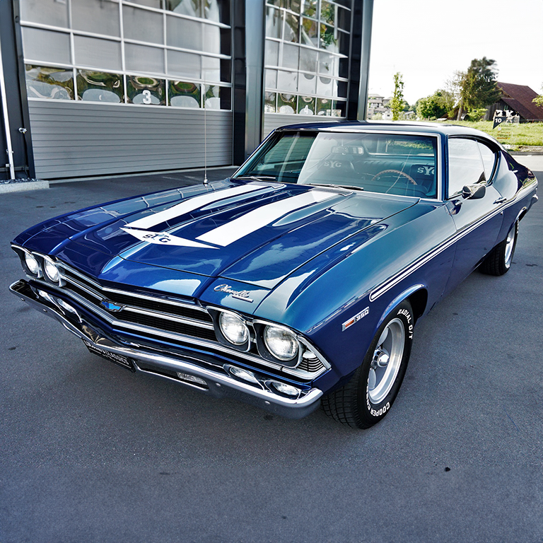 A blue car parked in front of a building.